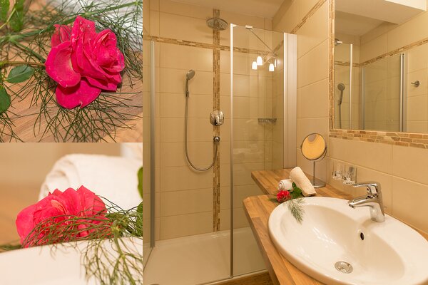 Modernes Badezimmer einer Ferienwohnung mit begehbarer Dusche, Waschbecken und Dekoration in St. Martin bei Lofer.