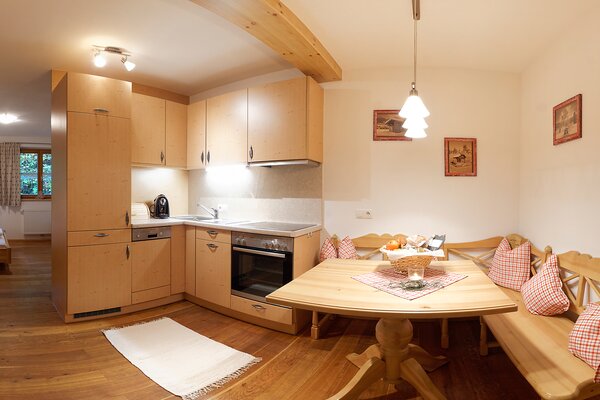Offener Küchenbereich mit gemütlicher Sitzecke aus Holz in einer Ferienwohnung im Mauthäusl Luftenstein.