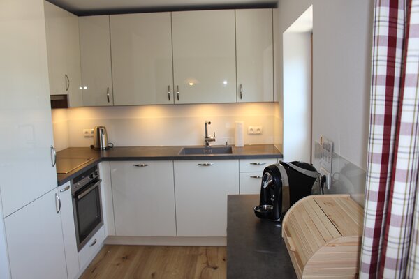 Moderne weiße Küchenzeile der Ferienwohnung Breithorn mit Kaffeemaschine und Holz-Brotkasten in Lofer.