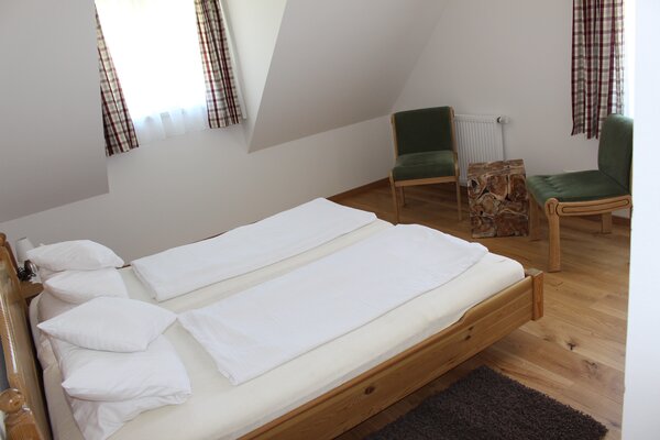 Gemütliches Schlafzimmer der Ferienwohnung Breithorn mit Doppelbett aus Holz und Dachschräge.