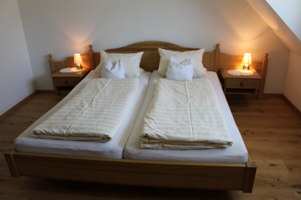 Gemütliches Doppelbett aus Holz im Schlafzimmer der Ferienwohnung Breithorn in Lofer.