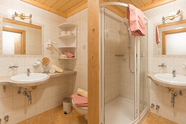 Geräumiges Badezimmer der Ferienwohnung Breithorn mit Glasdusche, zwei Waschbecken und hellen Fliesen.