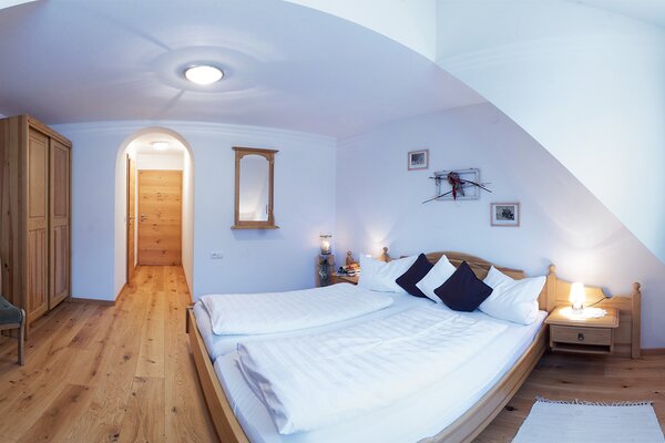Gemütliches Schlafzimmer der Ferienwohnung Breithorn mit Doppelbett, Holzboden und Dachschräge in Lofer.