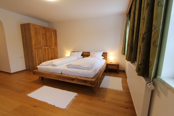 Gemütliches Schlafzimmer der Ferienwohnung Eiblhorn mit Massivholz-Doppelbett und Kleiderschrank in St. Martin.
