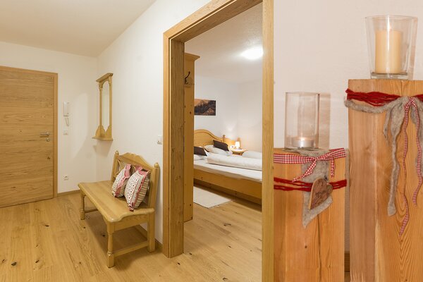 Gemütlicher Flur der Ferienwohnung Ochsenhorn mit Holzbank und Blick ins Schlafzimmer in Lofer.