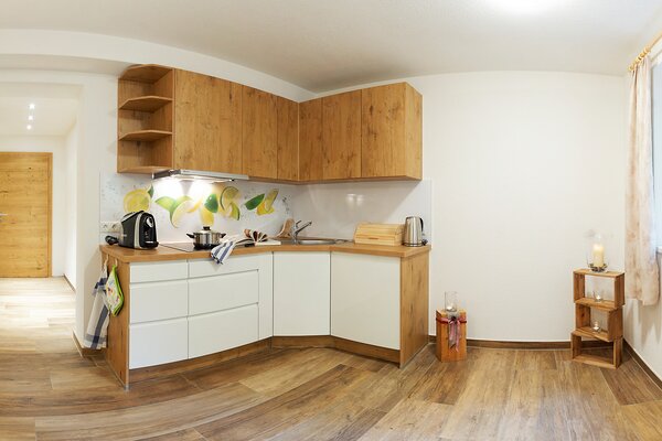 Moderne Holzküche der Ferienwohnung Ochsenhorn mit Zitronen-Rückwand und Flur in St. Martin bei Lofer.