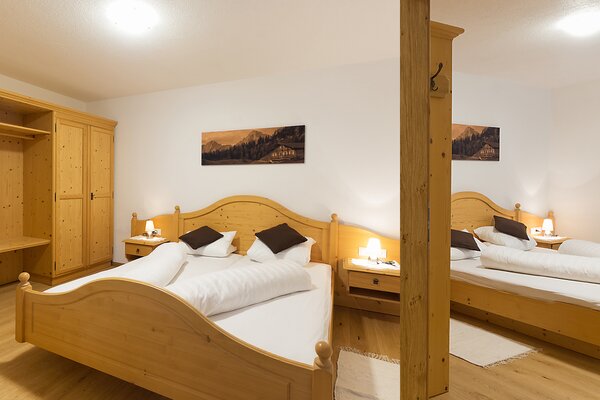 Gemütliches Schlafzimmer der Ferienwohnung Ochsenhorn mit Doppelbetten aus Holz in St. Martin bei Lofer.