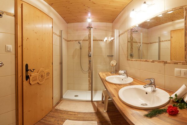 Badezimmer der Ferienwohnung Reifhorn mit Doppelwaschbecken, Glasdusche und Holzelementen in St. Martin bei Lofer.