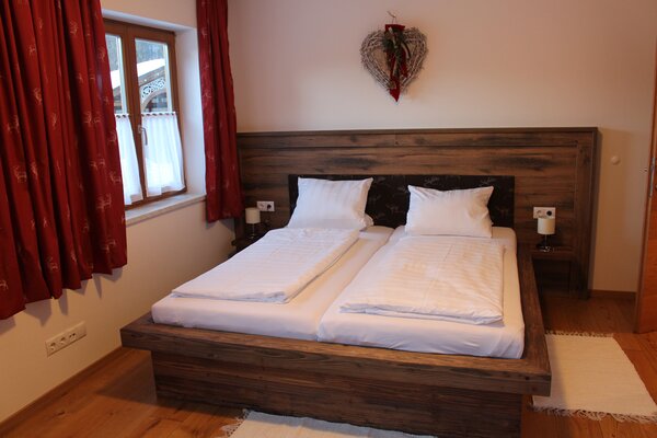 Gemütliches Schlafzimmer der Ferienwohnung Schihörndl mit Doppelbett aus Holz in St. Martin bei Lofer.