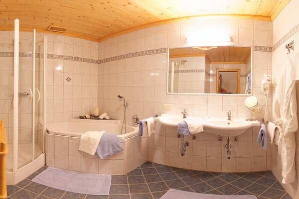Geräumiges Badezimmer der Ferienwohnung Vorderhorn mit Eckbadewanne, Dusche und Doppelwaschbecken in Lofer.